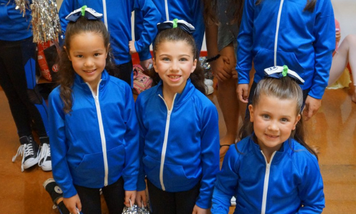 Dancers wearing blue costumes prepare to perform