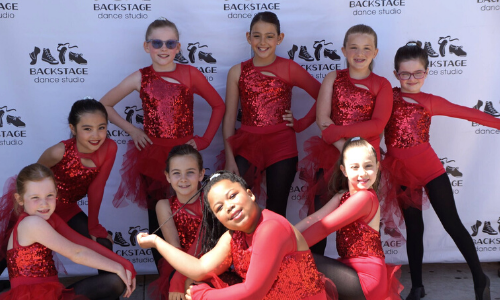 Dancers wearing red costumes prepare to perform