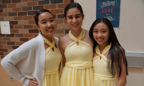 Dancers wearing yellow costumes prepare to perform
