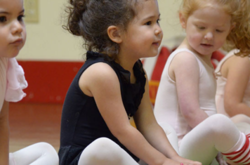 Young dancers sit and stretch