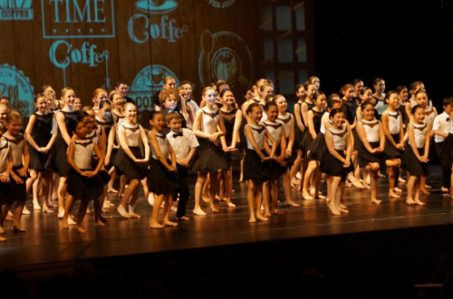 Large group of dancers wearing black and white on stage