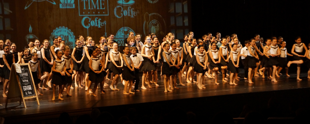 Large group of dancers wearing black and white on stage